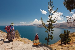 Two Women In Traditional Bolivian Clothes Standing On The Rock Close To The Titicaca Lake. Two Women In Traditional Bolivian Clothes Standing On The Rock Close To The Titicaca Lake.