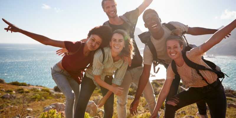 Millennial friends on a hiking trip reach the summit and have fun posing for photos