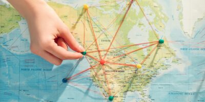 Partial view of woman with push pins, strings and world map